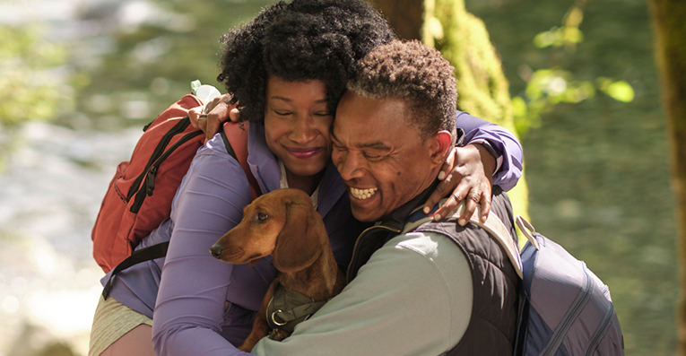Man and woman hugging with their dog